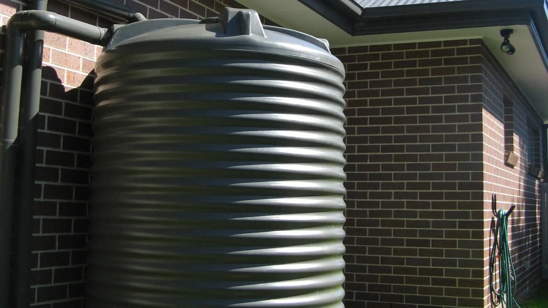 Benefits of water tank installation company Auckland image showing a water tank beside a home for Water Tank Installation Auckland.