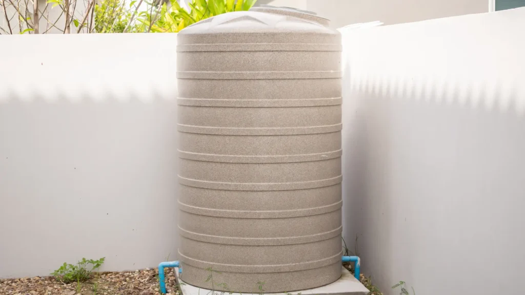 Water tank installation North Shore rainwater tank beside a home wall with connected pipework for water storage.